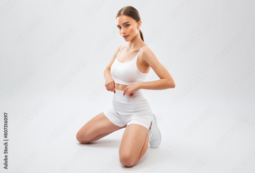 Beautiful attractive girl in white shorts and a top on a white background. The concept of sports and healthy lifestyle. Beautiful attractive girl in white shorts and a top on a white background. The concept of sports and healthy lifestyle.