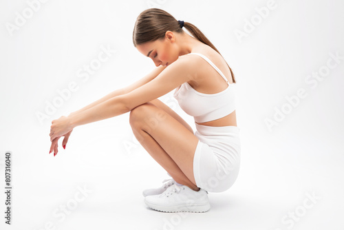 Beautiful attractive girl in white shorts and a top on a white background. The concept of sports and healthy lifestyle.