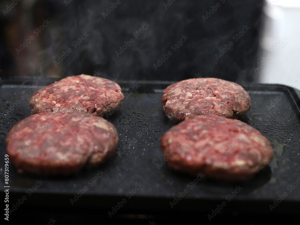 carne cruda de ternera friéndose a la parrilla para elaboración de hamburguesas carne cruda de ternera friéndose a la parrilla para elaboración de hamburguesas
