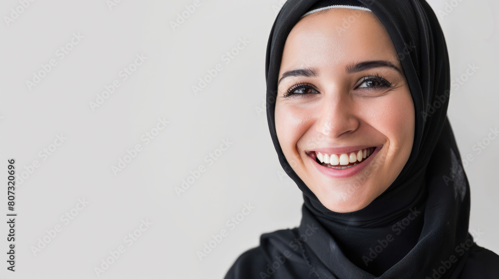 A positive Muslim woman happily smiling while wearing a traditional black hijab A positive Muslim woman happily smiling while wearing a traditional black hijab