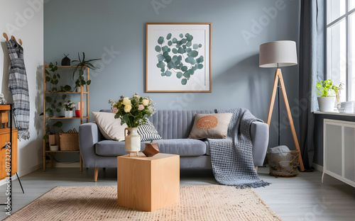 Interior design of scandinavian eucalyptus living room with gray sofa, wooden cube, flowers in vase, sculpture, pillow, plaid and personal accessories. Stylish home decor. Template. Copy space 