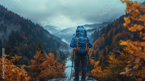 Solo Traveler with Backpack Admiring Autumn Mountainscape on Foggy Day photo