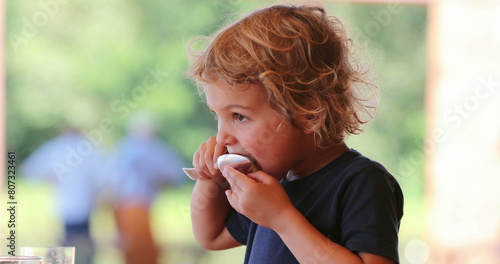 Little blond boy eating melon fruit dessert with spoon casual and candid photo