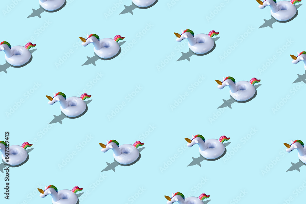 Fototapeta premium Creative pattern with inflatable unicorn pool toy on blue background. Minimal summer concept.