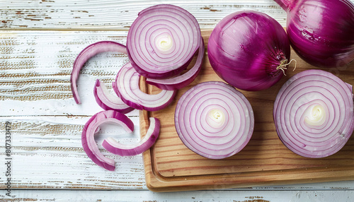 Board with slices of fresh red onion on white wooden background