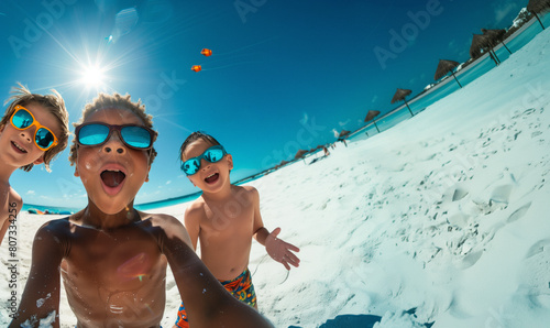 children take a photo expressing open-mouthed wonder and joy, with colorful kites and clear blue sky in the background on a tropical white sand beach.