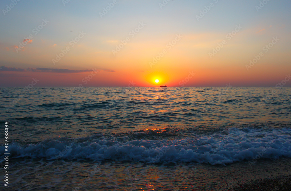 Obraz premium A beautiful sunset over the sea with orange clouds, and a calm tide