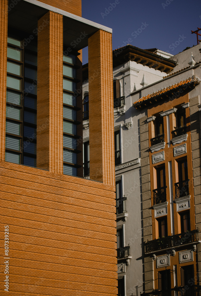 Obraz premium Close up detail of modern orange brick building facade with blue tinted windows. Office glass wall pattern. Urban architecture. Industrial style house