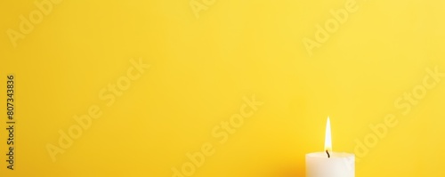 Yellow background with white thin wax candle with a small lit flame for funeral grief death dead sad emotion with copy space texture for display products