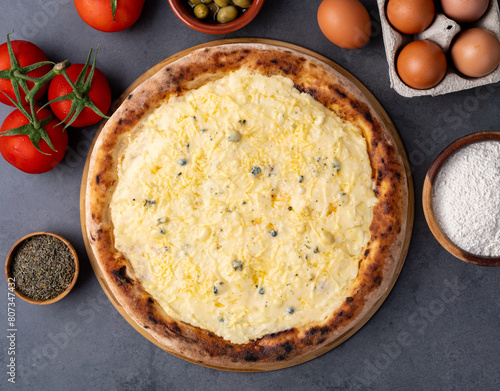 Four cheese style pizza over stone background with tomatoes, olives and oregano