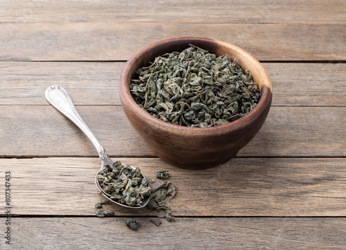 Dried green tea leaves on a bowl over wooden table