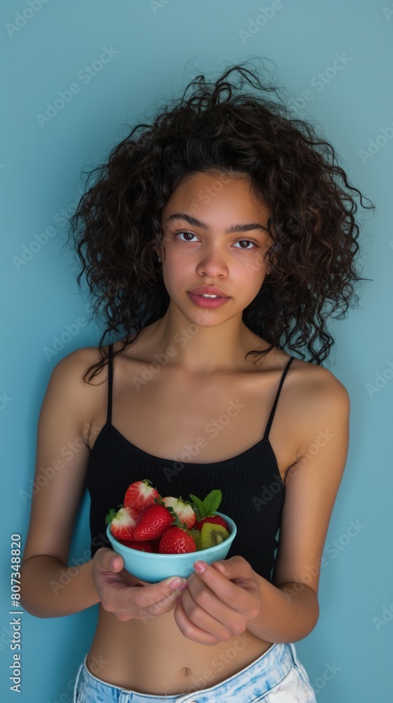 A young mixed race woman holds a bowl filled with fresh strawberries A young mixed race woman holds a bowl filled with fresh strawberries