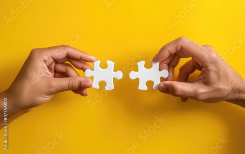 Two hands connecting puzzle pieces against a vivid yellow background.