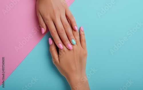 Woman s hands with pastel pink nails on a dual-tone background.