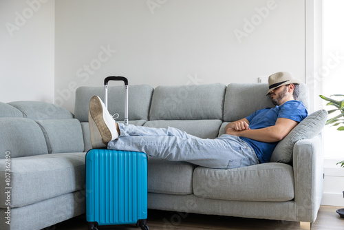 Man resting on the sofa with travel suitcases prepared