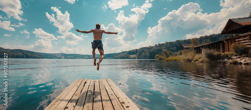 Young man jumping into the lake from the jetty. Activity on summer holidays