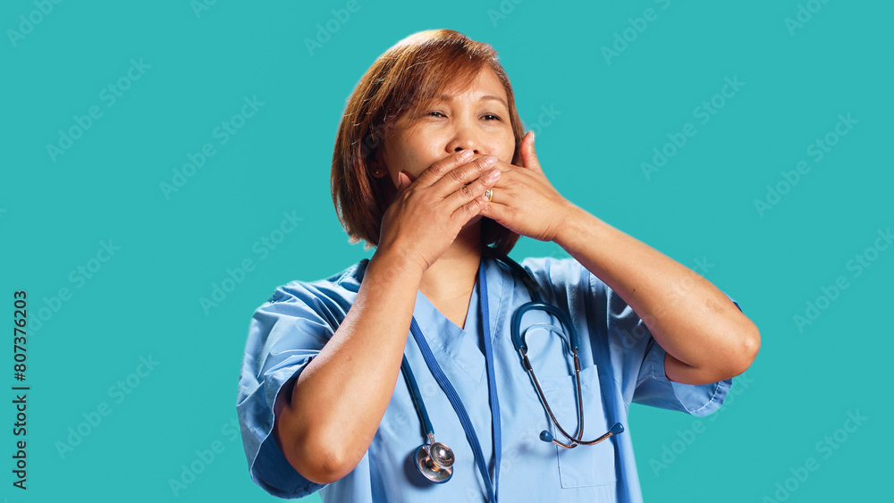Certified nurse covering mouth with hands, holding back from saying rude thoughts. Hospital employee silencing herself, abstaining from speaking, isolated over studio background, close up Certified nurse covering mouth with hands, holding back from saying rude thoughts. Hospital employee silencing herself, abstaining from speaking, isolated over studio background, close up