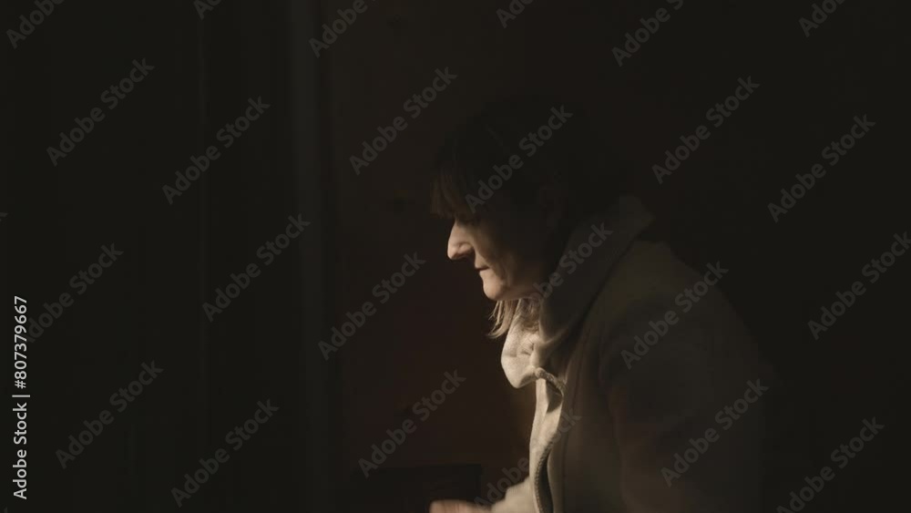 Religious Catholic woman crossing herself and praying with folded arms during confession in church side view. Female Christian sitting near confessional booth Religious Catholic woman crossing herself and praying with folded arms during confession in church side view. Female Christian sitting near confessional booth