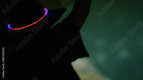 A woman in a cowboy hat dances at an outdoor concert with glow sticks photo