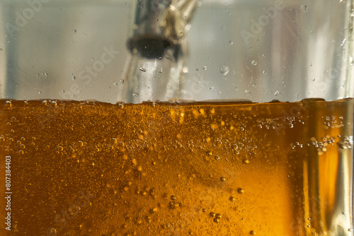 Gasoline flowing from a pump over a glass container. Fuel supply concept. Close-up 2