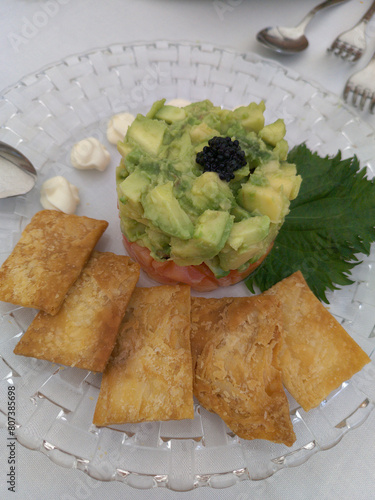 Avocado timbale with salmon decorated on a glass plate.  