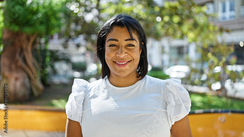 Smiling hispanic woman in park with greenery