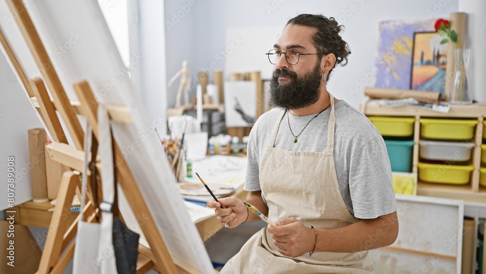 Hispanic man painting canvas in art studio