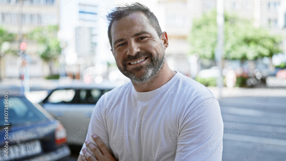 Handsome mature hispanic man with grey hair smiling outdoors in an urban city setting. Handsome mature hispanic man with grey hair smiling outdoors in an urban city setting.