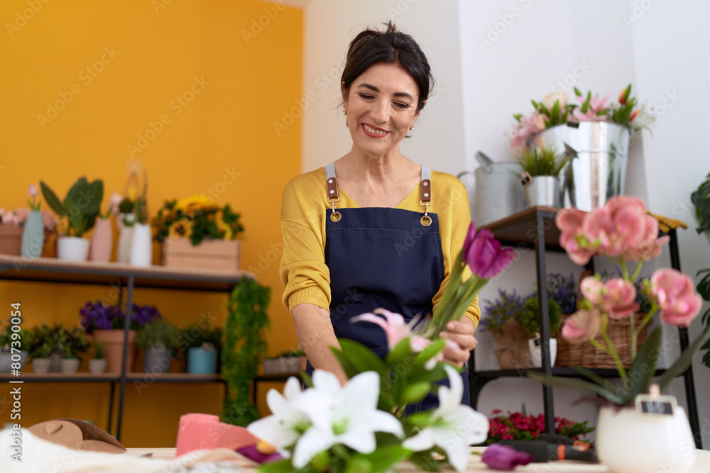Middle age hispanic woman florist make bouquet of flowers at flower shop Middle age hispanic woman florist make bouquet of flowers at flower shop