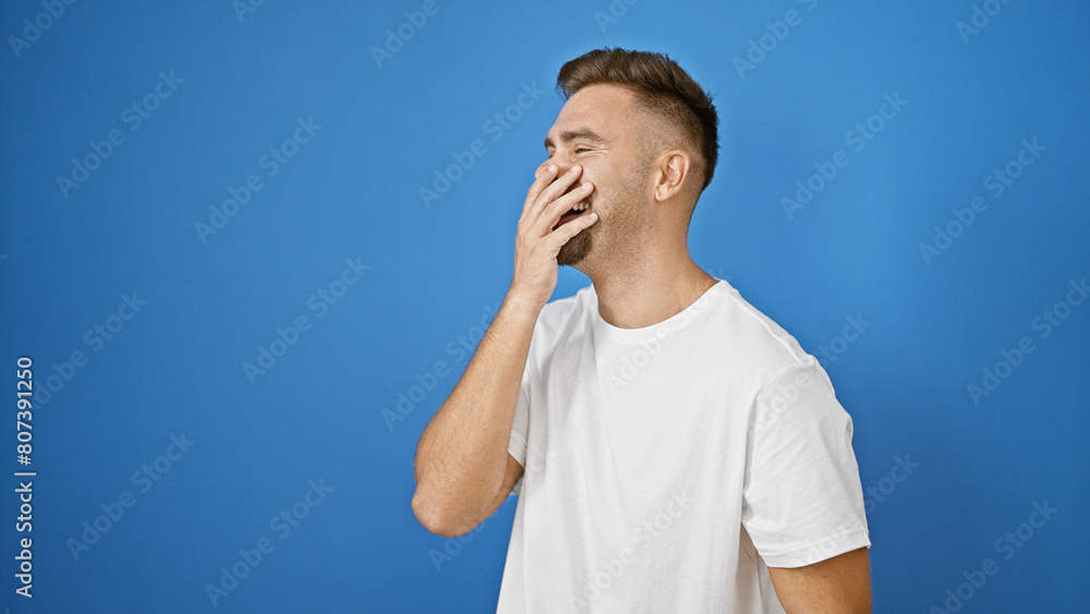 A smiling young hispanic man with a beard posing casually outdoors against a blue wall, exuding charm and confidence. A smiling young hispanic man with a beard posing casually outdoors against a blue wall, exuding charm and confidence.