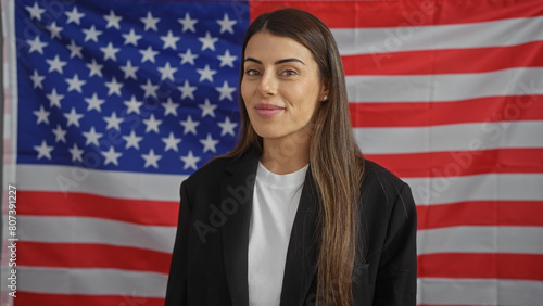 Portrait of a confident young hispanic woman in formal attire before an american flag photo