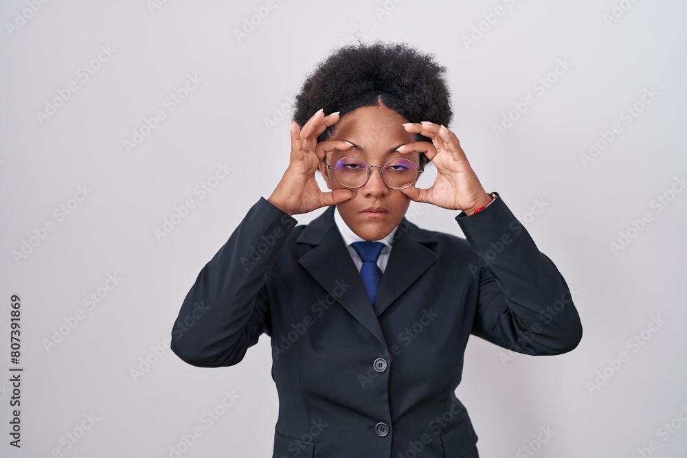 Beautiful african woman with curly hair wearing business jacket and glasses trying to open eyes with fingers, sleepy and tired for morning fatigue Beautiful african woman with curly hair wearing business jacket and glasses trying to open eyes with fingers, sleepy and tired for morning fatigue