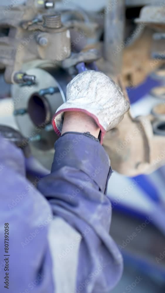 close up view of mechanic hands changing brake disc in a mechanical workshop close up view of mechanic hands changing brake disc in a mechanical workshop