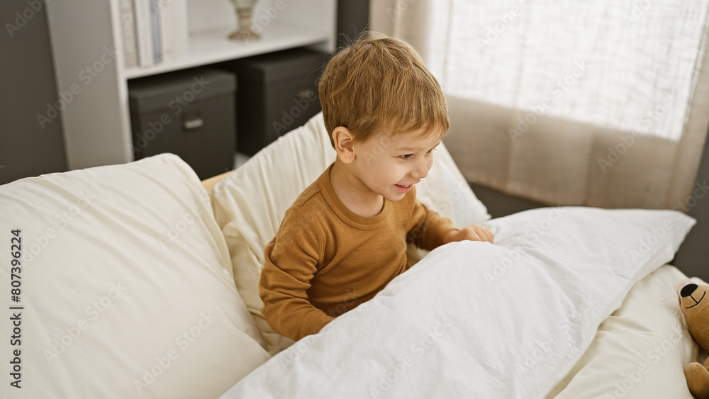 A smiling young boy plays on a bed in a well-lit cozy bedroom, embodying innocence and joy. A smiling young boy plays on a bed in a well-lit cozy bedroom, embodying innocence and joy.