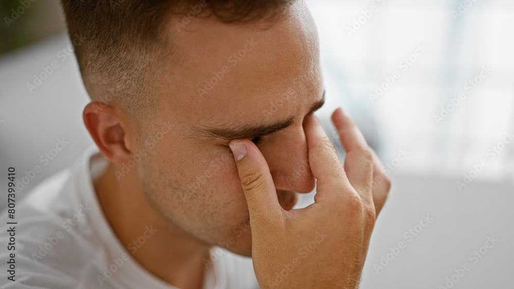 A thoughtful young hispanic man indoors touching his face, showcasing stress, contemplation, or health concerns. A thoughtful young hispanic man indoors touching his face, showcasing stress, contemplation, or health concerns.