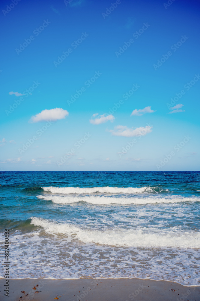 waves crashing on beach with clouds in blue sky waves crashing on beach with clouds in blue sky