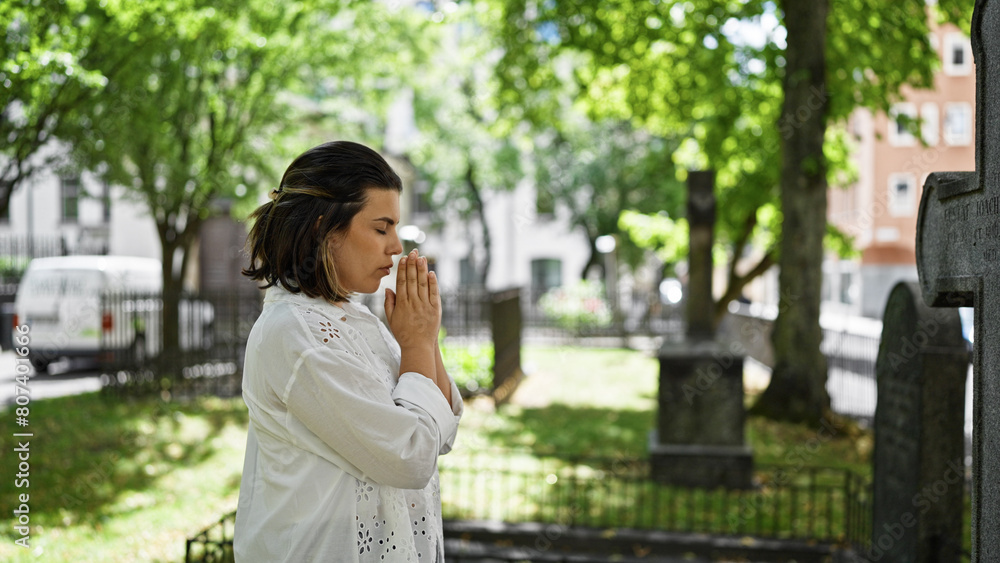 Beautiful young hispanic woman praying and mourning by tombstone at graveyard Beautiful young hispanic woman praying and mourning by tombstone at graveyard