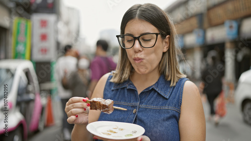 Stunning hispanic woman with glasses savors fresh wagyu beef stick meal at traditional tsukiji outer market street shop, tokyo