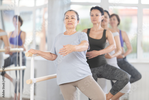 Woman, along with like-minded people, is engaged in ballet studio for amateurs