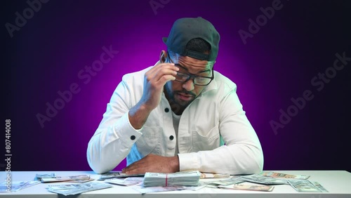 A weary businessman takes off his glasses and lays his head down to sleep on a desk covered with a large amount of cash, illustrating the exhaustion after financial endeavors. Camera 8K RAW. 