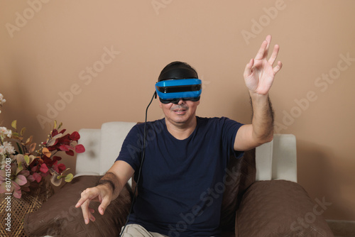 Latin adult with mixed reality headset playing in living room, virtual reality video game concept playing with his hands