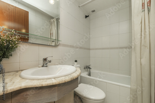 Bathroom of a house with wooden sink cabinet with beveled mirror on the wall and bathtub with curtains