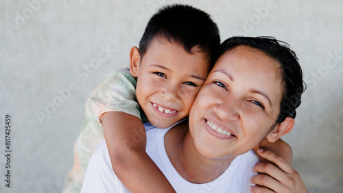 Happy Latin mother and son having fun hugging each other. Family relationship and love concept. Focus on child face