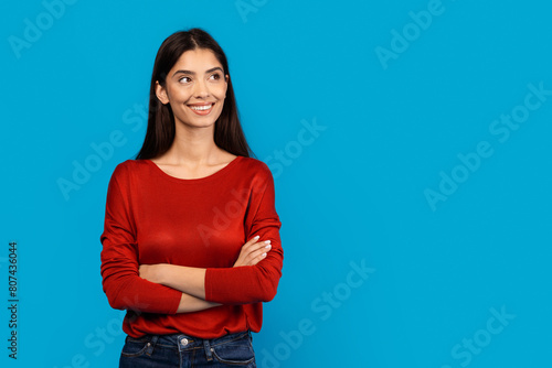 Fotografía A woman wearing a red sweater stands with her arms crossed in a neutral pose