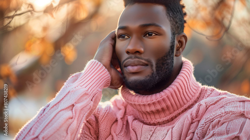 African american man in a pink sweater in autumn park, trend for new masculinity photo