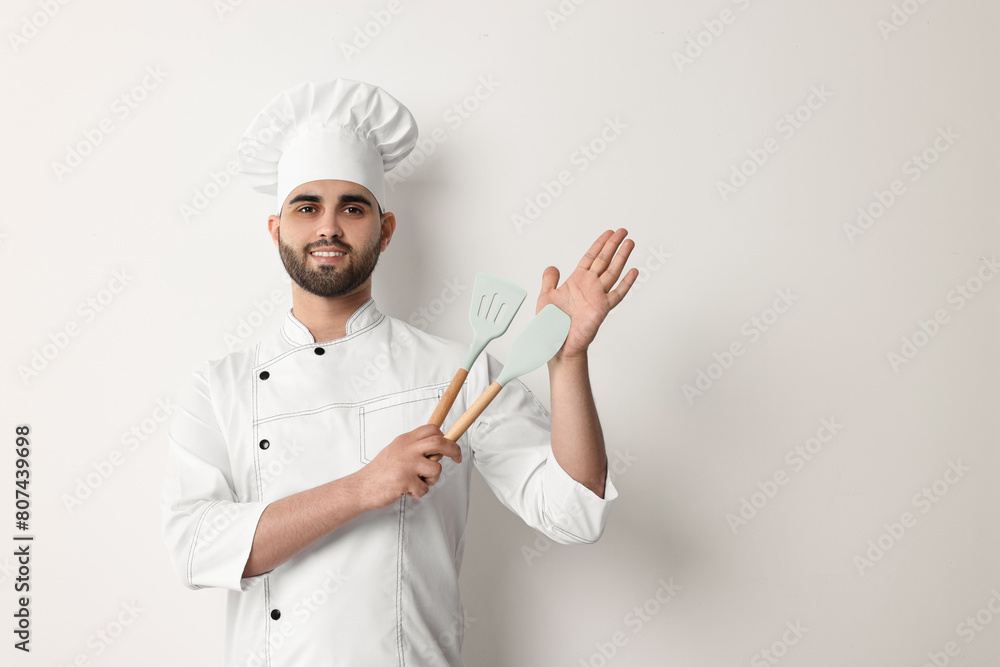 Professional chef holding kitchen utensils on white background Professional chef holding kitchen utensils on white background