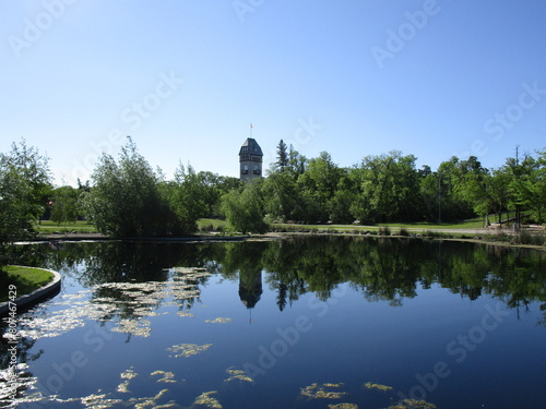 placid pond reflects trees and distant tower