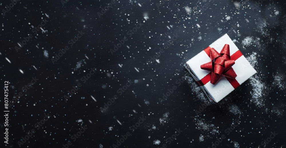 Decorative gift box with red bow and long ribbon on a dark snow background. Greeting card design for Christmas, New Year, with copy space. Decorative gift box with red bow and long ribbon on a dark snow background. Greeting card design for Christmas, New Year, with copy space.