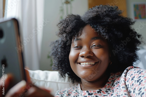 Phone selfie made by smiling african american girl with natural soft light and colors in her room on the background photo