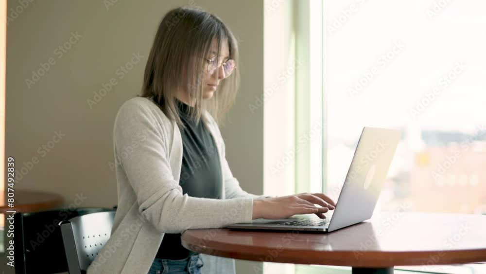 young professional woman using a laptop at round table bathed in natural light from a nearby window business casual attire convey productivity and modern work dynamics remote work, entrepreneurship young professional woman using a laptop at round table bathed in natural light from a nearby window business casual attire convey productivity and modern work dynamics remote work, entrepreneurship